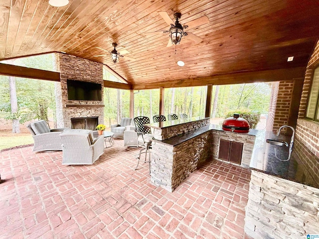 view of patio featuring an outdoor stone fireplace, an outdoor kitchen, a sink, and a ceiling fan