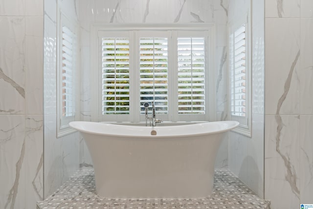 full bathroom with a freestanding tub and tile walls