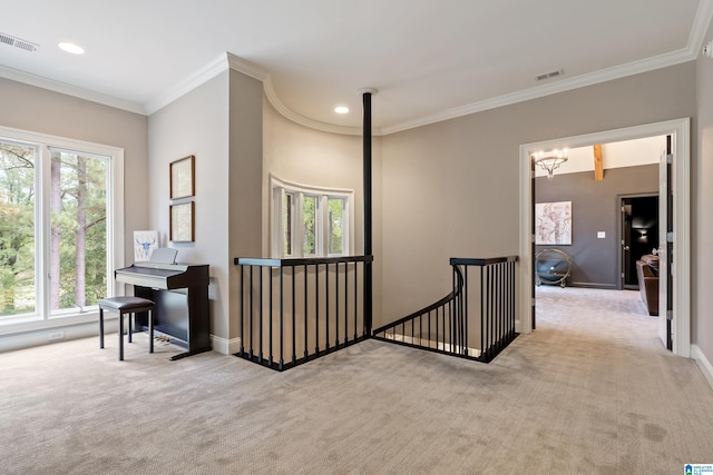 hall with carpet, an upstairs landing, visible vents, and crown molding