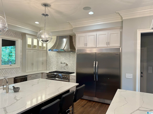 kitchen with dark wood-style floors, wall chimney exhaust hood, ornamental molding, and premium appliances