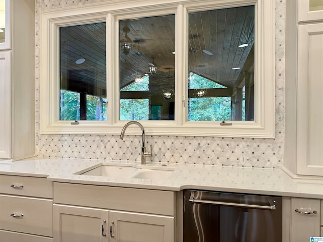 kitchen with glass insert cabinets, a sink, backsplash, and stainless steel dishwasher