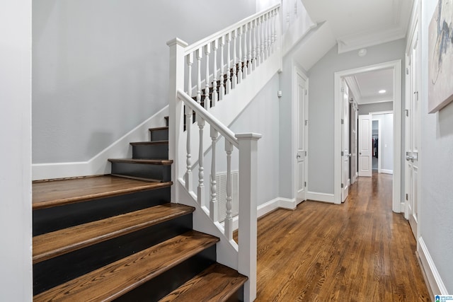 stairs with crown molding, wood finished floors, visible vents, and baseboards