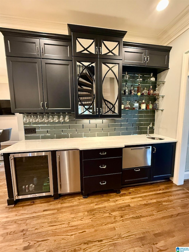 bar with beverage cooler, ornamental molding, refrigerator, wet bar, and a sink