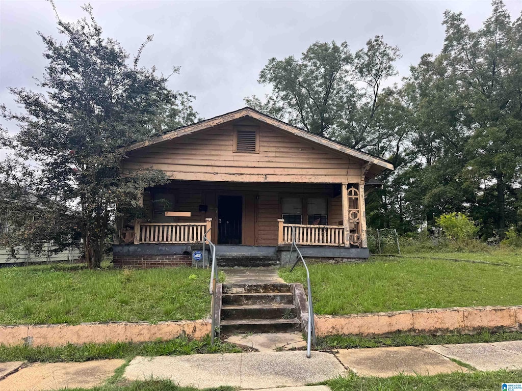 bungalow-style house with covered porch and a front lawn