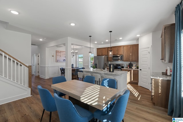 dining space with sink, dark hardwood / wood-style floors, and an inviting chandelier