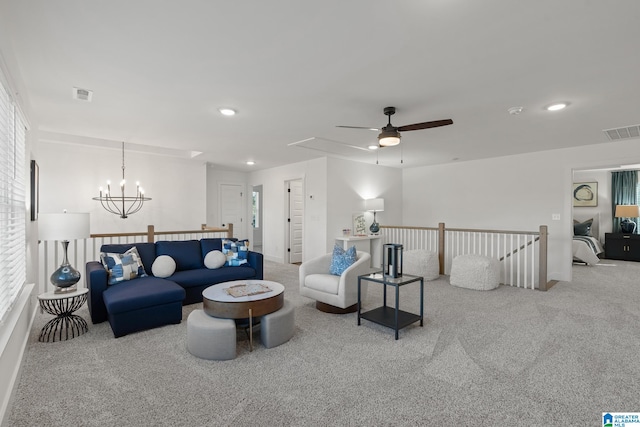 carpeted living room featuring ceiling fan with notable chandelier