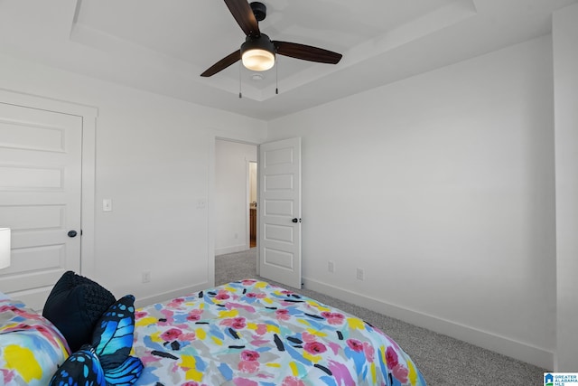 bedroom with carpet flooring, a tray ceiling, and ceiling fan