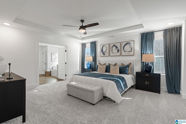 bedroom with ceiling fan, a raised ceiling, and multiple windows