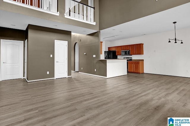 unfurnished living room featuring a towering ceiling and light wood-type flooring