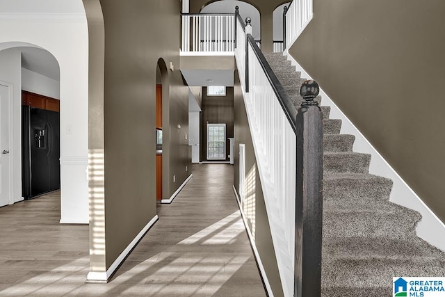 stairway with ornamental molding and wood-type flooring