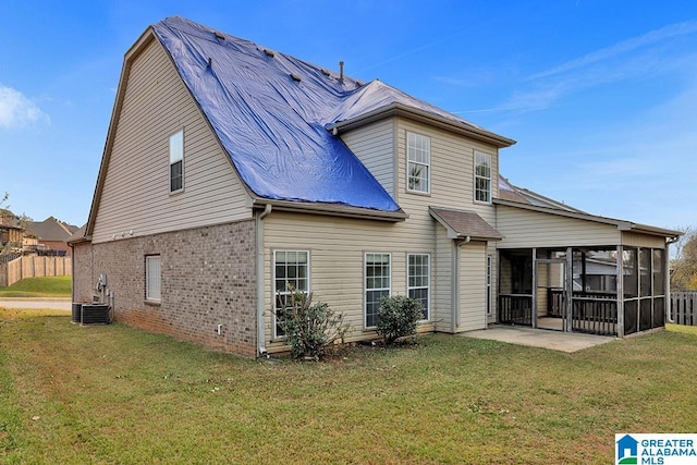 rear view of house featuring a patio, a lawn, and a sunroom