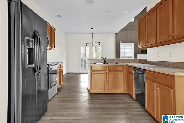 kitchen featuring kitchen peninsula, hardwood / wood-style floors, hanging light fixtures, black appliances, and sink