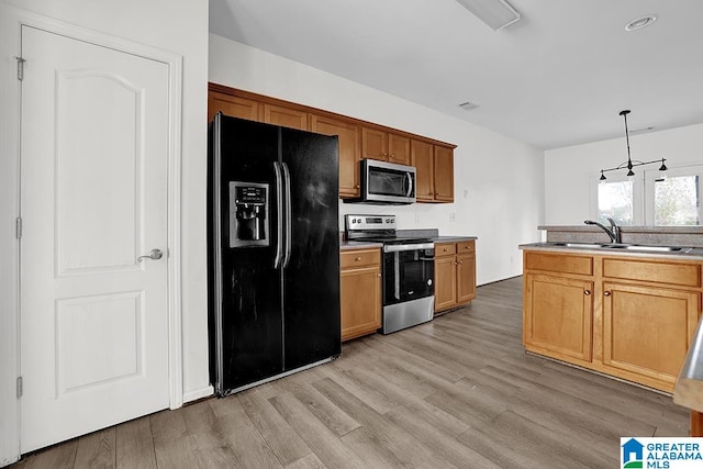 kitchen with appliances with stainless steel finishes, sink, hanging light fixtures, and light hardwood / wood-style floors