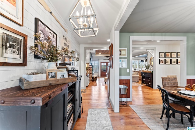 hallway with an inviting chandelier and light wood-type flooring