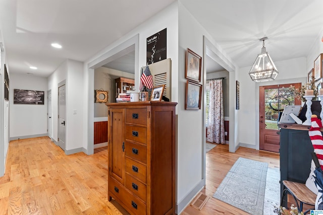 hall with a chandelier and light wood-type flooring