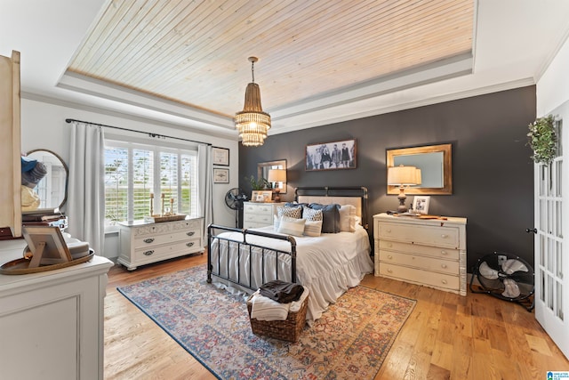 bedroom featuring a tray ceiling, wooden ceiling, crown molding, light hardwood / wood-style flooring, and an inviting chandelier