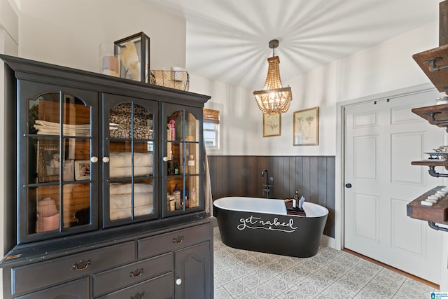 bathroom with wood walls, an inviting chandelier, and a bathing tub