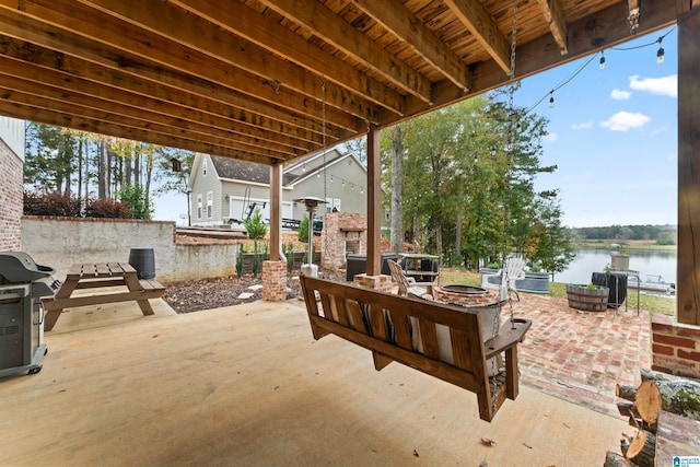 view of patio / terrace with an outdoor fire pit, area for grilling, and a water view