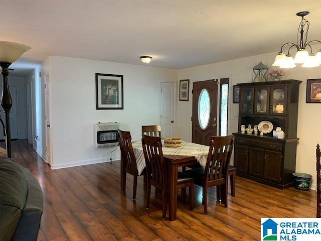 dining room featuring an inviting chandelier, heating unit, and dark hardwood / wood-style floors