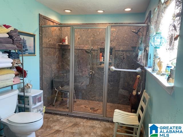 bathroom with a shower with door and toilet