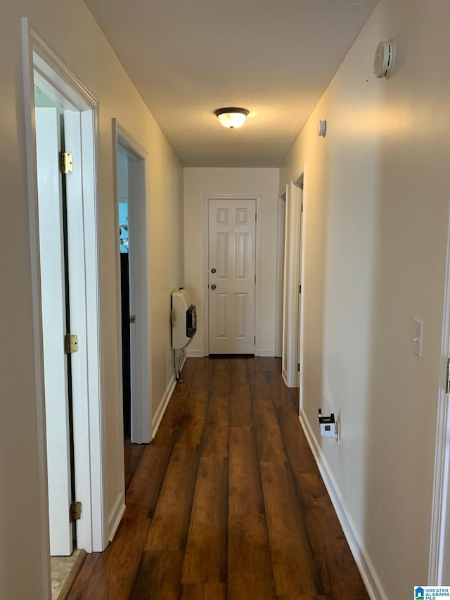 corridor with heating unit and dark hardwood / wood-style floors