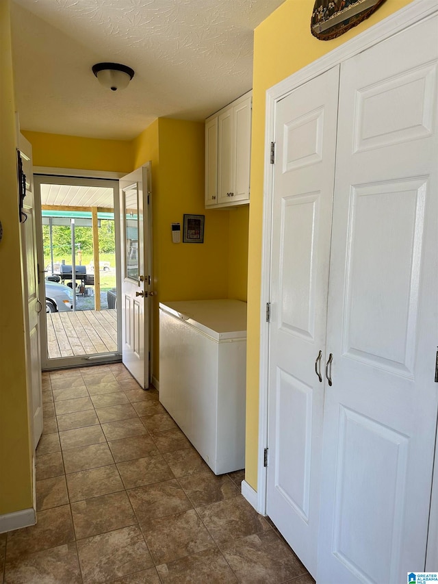 laundry room featuring cabinets, a textured ceiling, and dark tile patterned floors