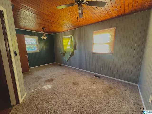 carpeted empty room with wood walls, wood ceiling, and ceiling fan