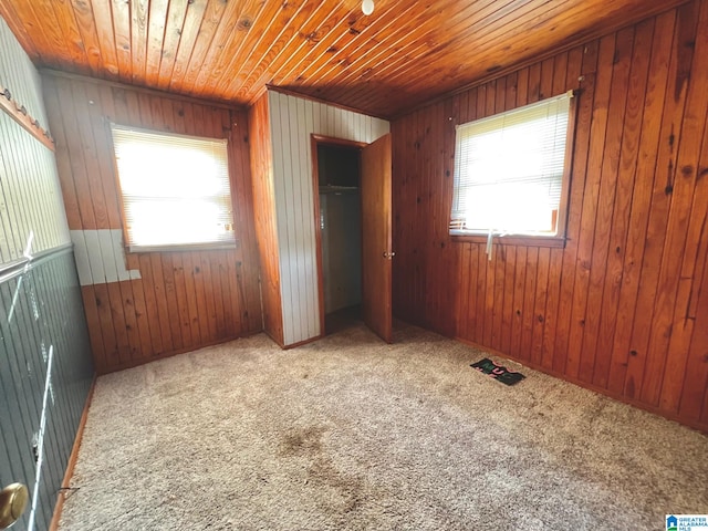 unfurnished bedroom with wood ceiling, wood walls, a closet, and carpet flooring