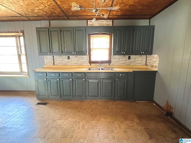 kitchen with wood walls, sink, a healthy amount of sunlight, and tasteful backsplash