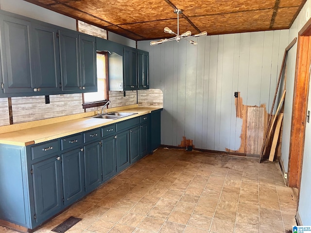 kitchen with tasteful backsplash, wooden walls, sink, and pendant lighting