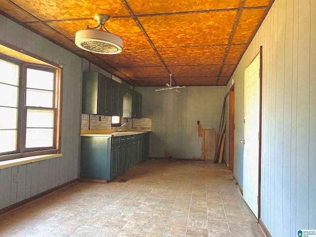 kitchen featuring a notable chandelier, wood walls, tasteful backsplash, and sink