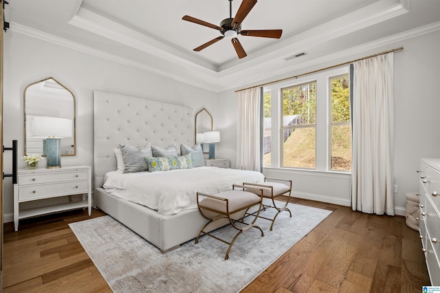 bedroom featuring ornamental molding, dark hardwood / wood-style floors, a tray ceiling, and ceiling fan