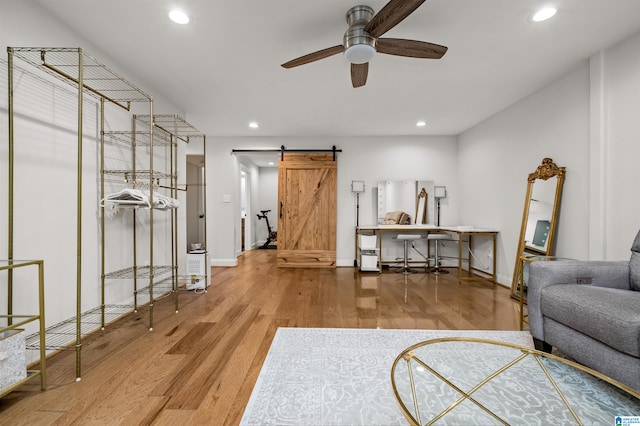 living room featuring a barn door, hardwood / wood-style flooring, and ceiling fan