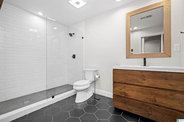 bathroom featuring toilet, vanity, a tile shower, and tile patterned flooring