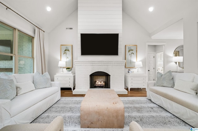 living room featuring high vaulted ceiling, wood-type flooring, and a fireplace