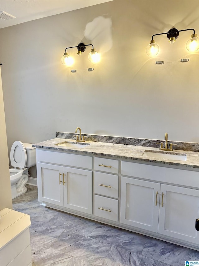 bathroom featuring double vanity, visible vents, a sink, and toilet
