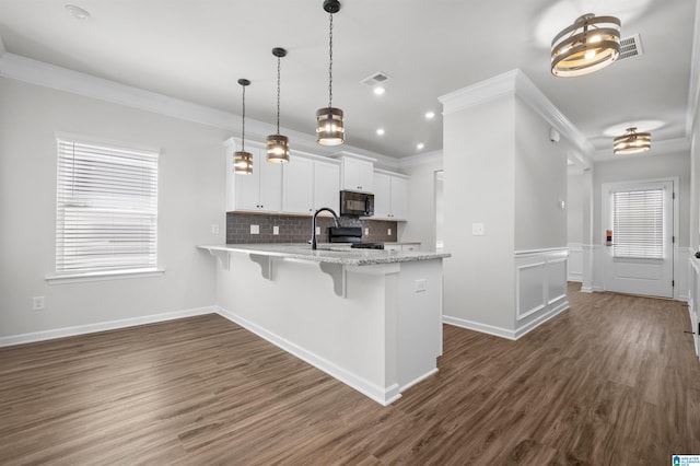 kitchen featuring a kitchen bar, black appliances, white cabinets, dark hardwood / wood-style floors, and hanging light fixtures