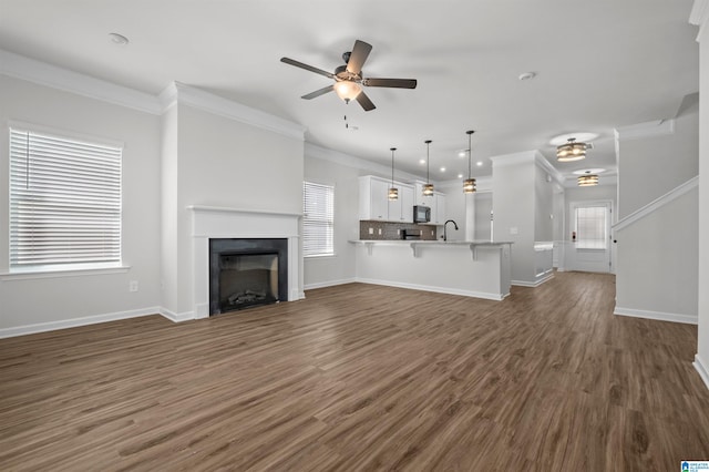 unfurnished living room with crown molding, sink, ceiling fan, and dark wood-type flooring