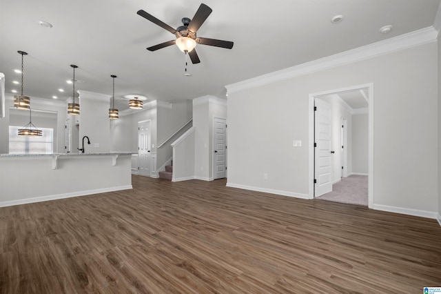 unfurnished living room featuring crown molding, ceiling fan, dark wood-type flooring, and sink