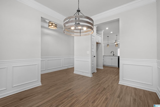 unfurnished dining area featuring a chandelier, dark hardwood / wood-style floors, crown molding, and sink