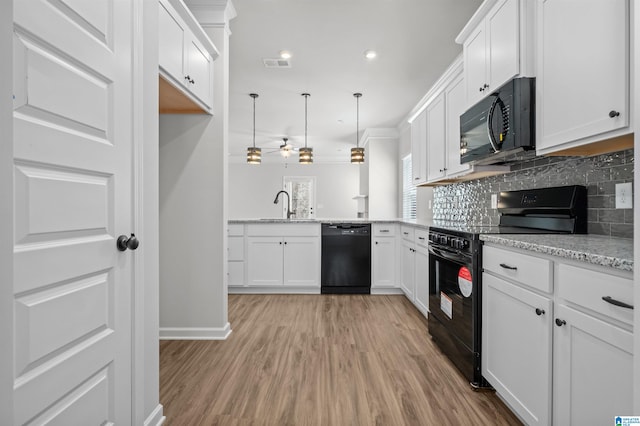 kitchen with black appliances, decorative light fixtures, white cabinetry, and light hardwood / wood-style flooring