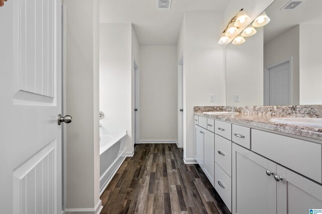 bathroom with vanity, a tub to relax in, and hardwood / wood-style flooring