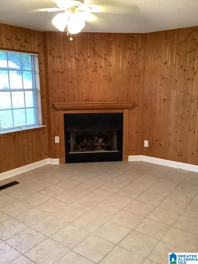 unfurnished living room with wooden walls and ceiling fan