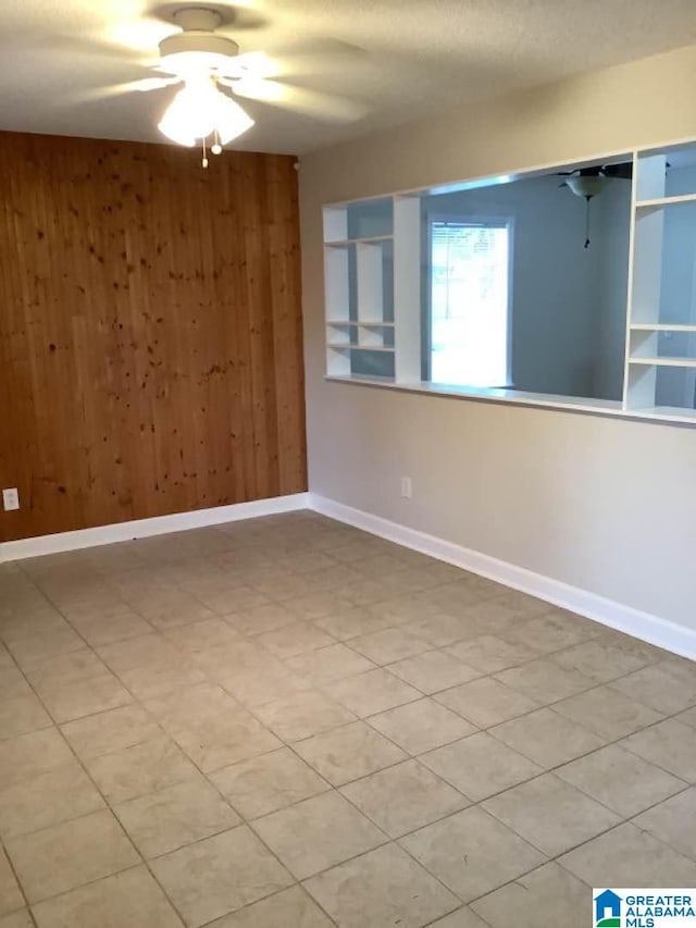 spare room featuring ceiling fan and wood walls