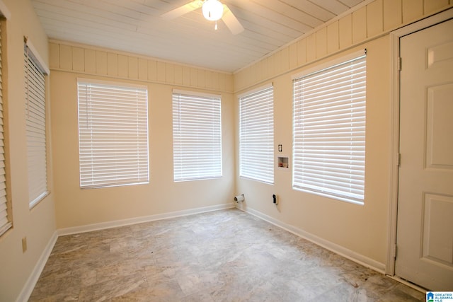 empty room featuring a wealth of natural light, wood walls, wood ceiling, and ceiling fan