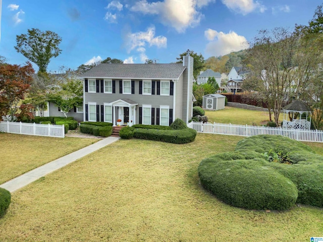 colonial inspired home with a storage shed and a front lawn