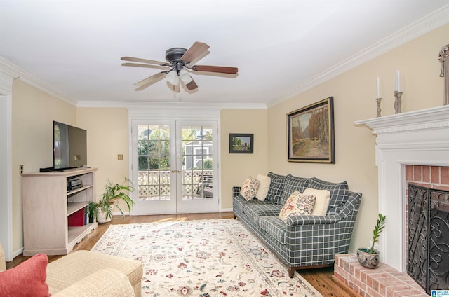 living room with ceiling fan, wood-type flooring, a brick fireplace, crown molding, and french doors