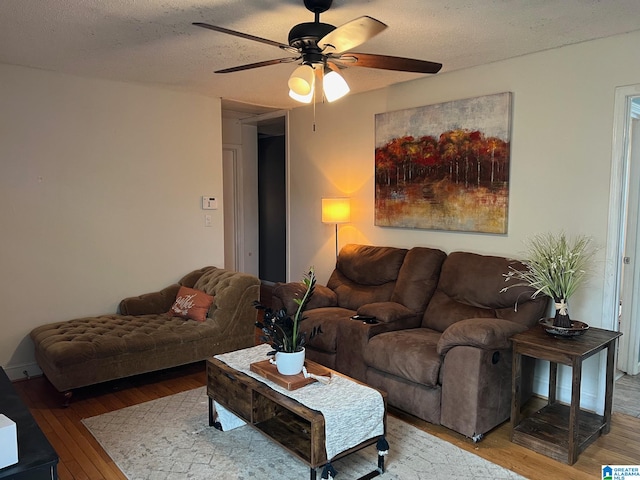 living room featuring ceiling fan, a textured ceiling, and light hardwood / wood-style floors