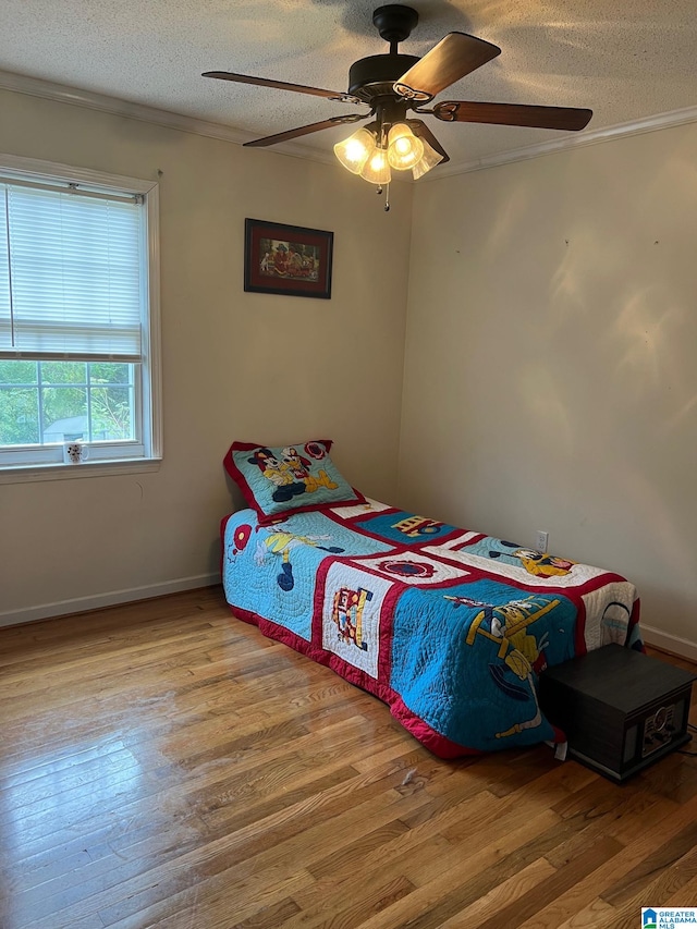 bedroom with crown molding, a textured ceiling, light wood-type flooring, and ceiling fan