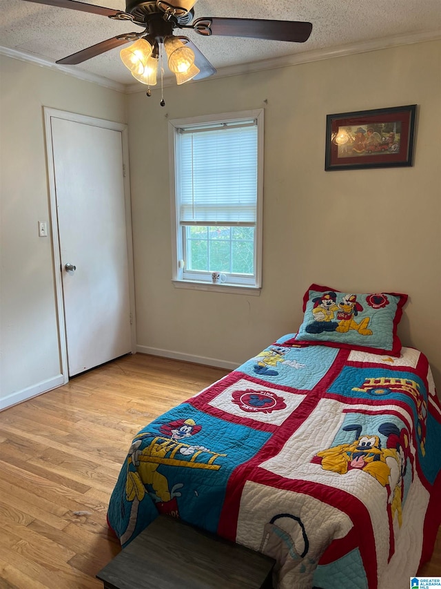 bedroom featuring crown molding, light hardwood / wood-style flooring, a textured ceiling, and ceiling fan